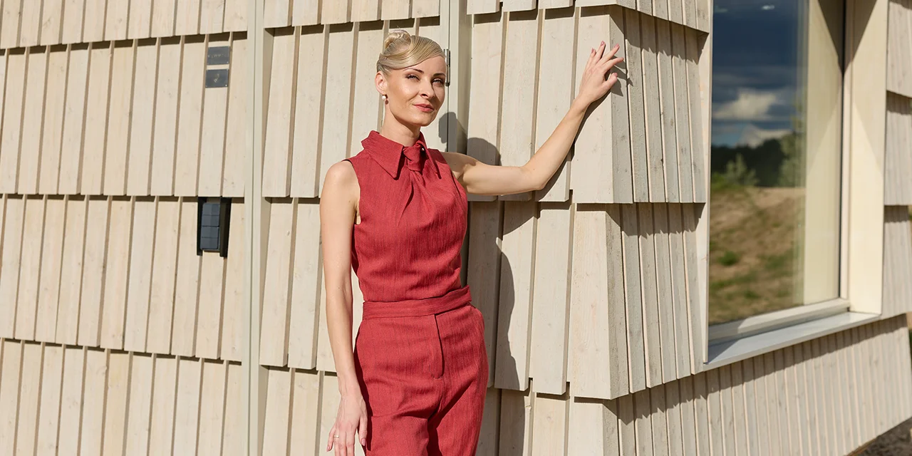 Woman resting her hand on the shingled timber facade of a Steam Spirit sauna